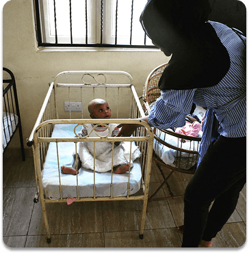 Baby in crib with caretaker - Caregiver attending to an infant in a hospital crib